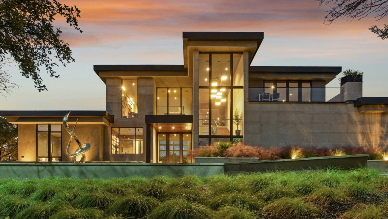 Glass-walled modern house lit up at dusk