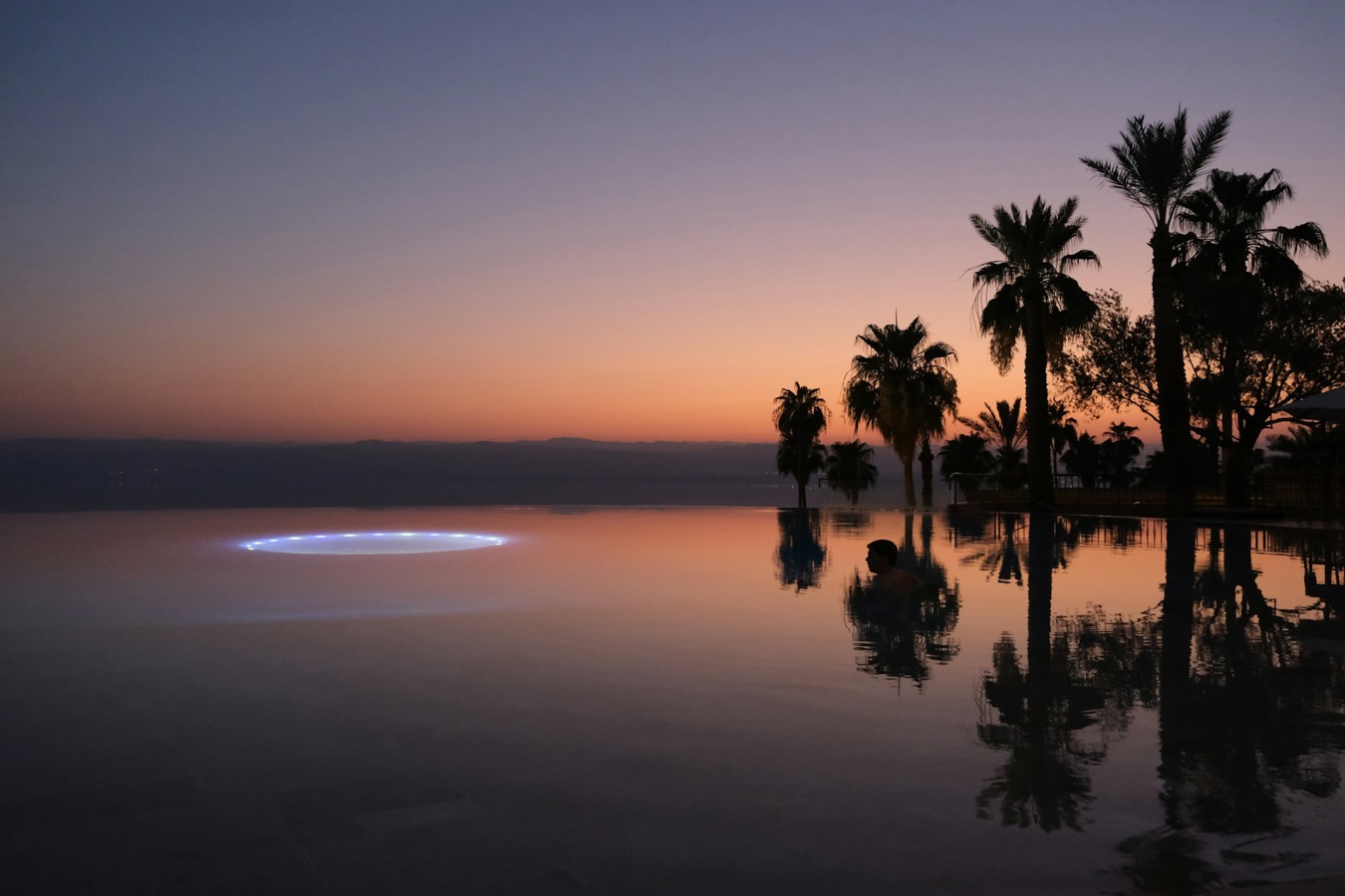 Infinity pool edge and palms at sunset