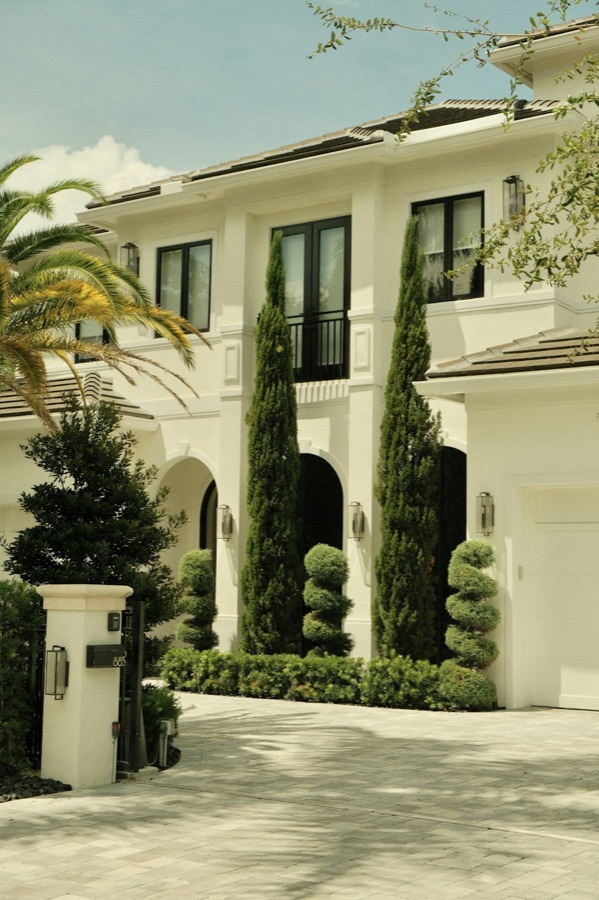 White mansion entrance with topiaries and palms